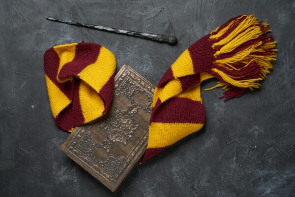 Yellow and maroon striped scarf with leather book and wand.